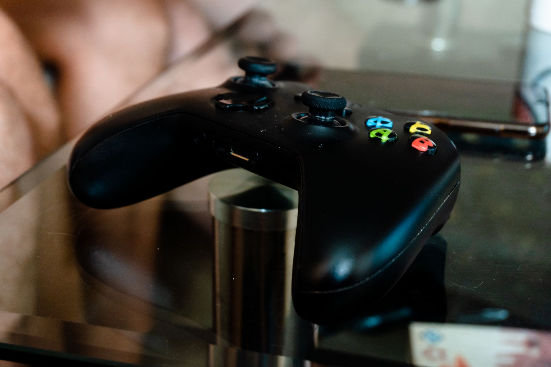 Gros plan d'une manette de jeu vidéo noire moderne posée sur une table en verre à l'intérieur.