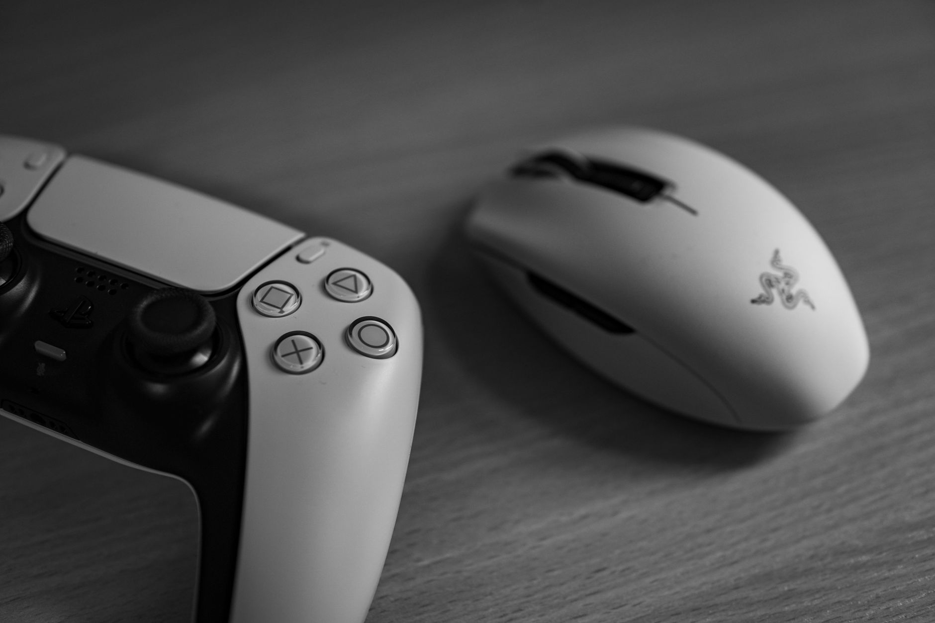 Monochrome image of a gaming controller and mouse on a desk, highlighting modern technology.